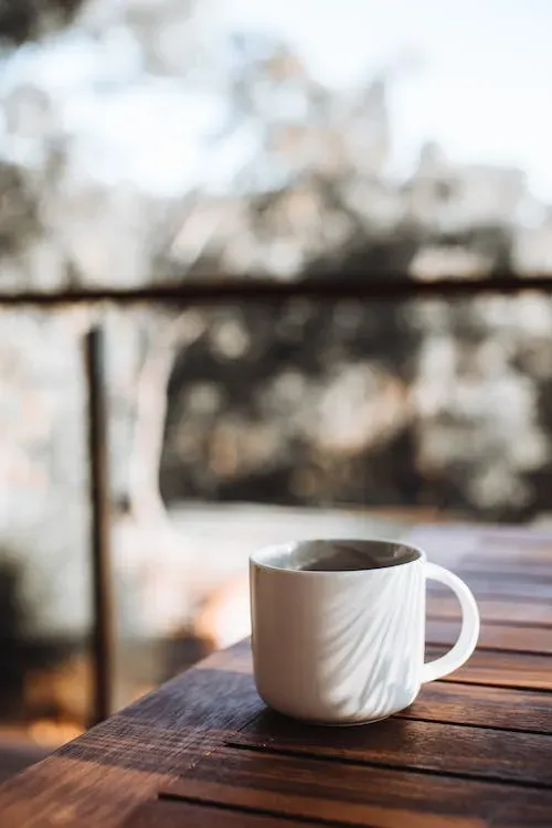 Free White ceramic cup of hot drink placed on brown wooden table on terrace Stock Photo