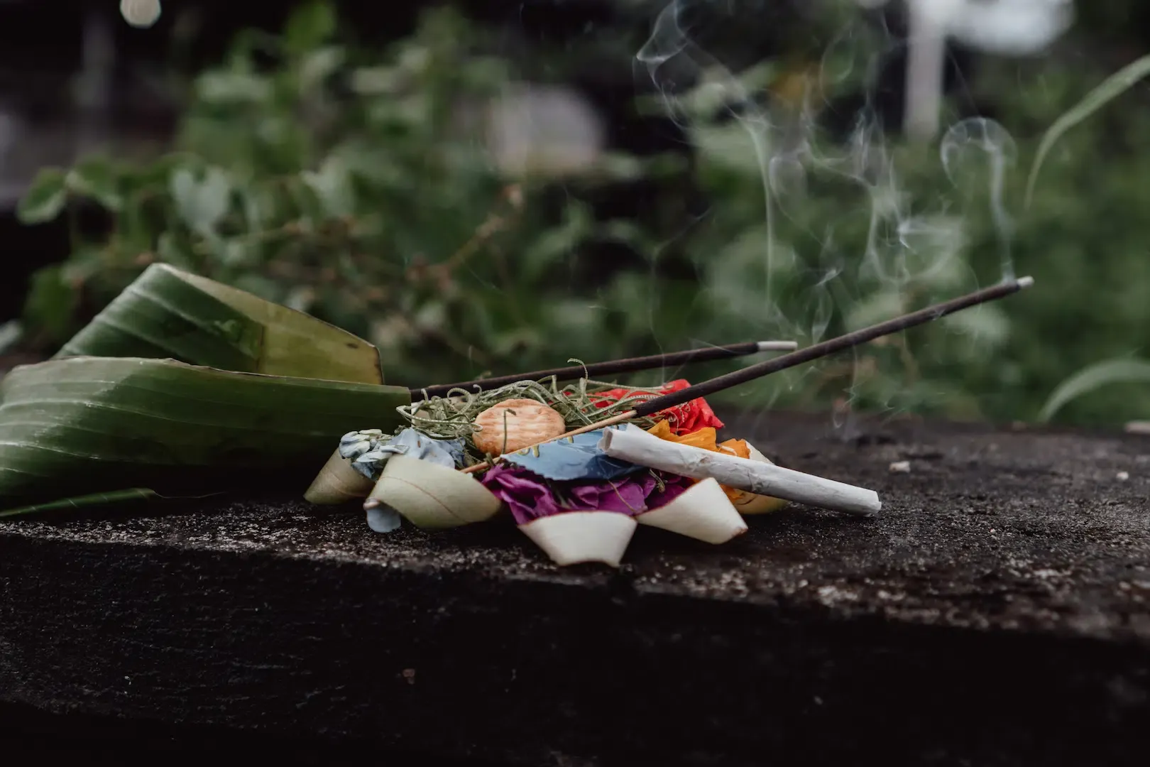 Incense stick burning atop a colorful floral offering