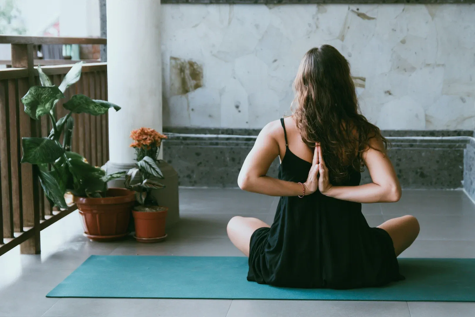 Woman meditating in prayer position on a balcony yoga mat