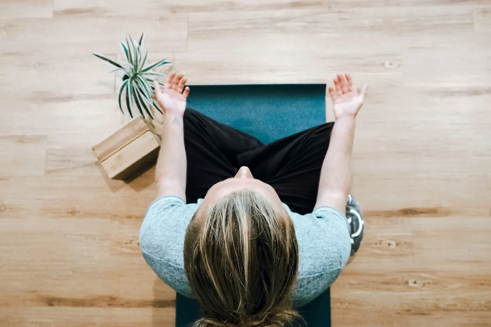 Overhead view of a person meditating cross-legged with arms raised