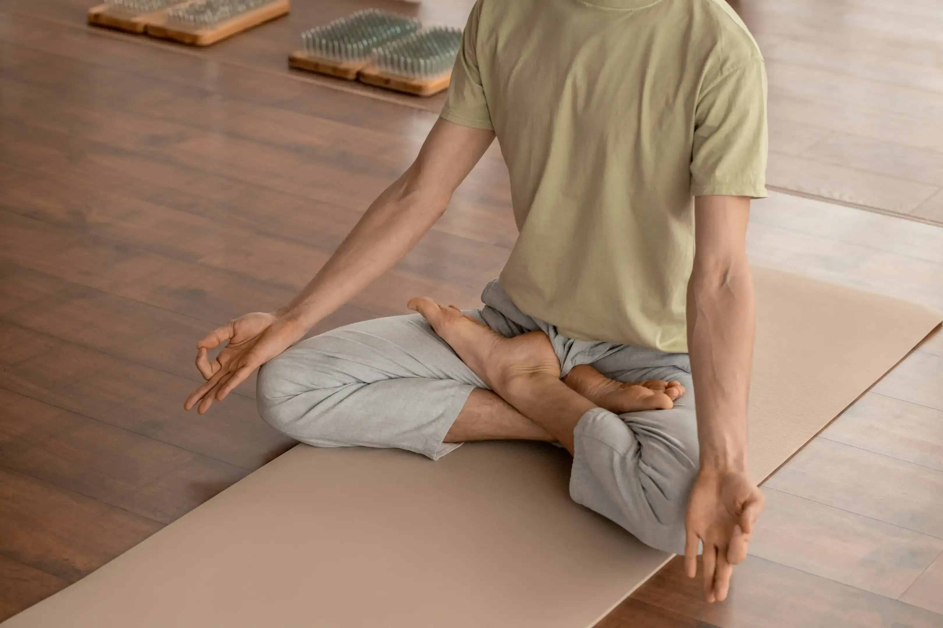 Person sitting cross-legged in meditation with hand in a mudra