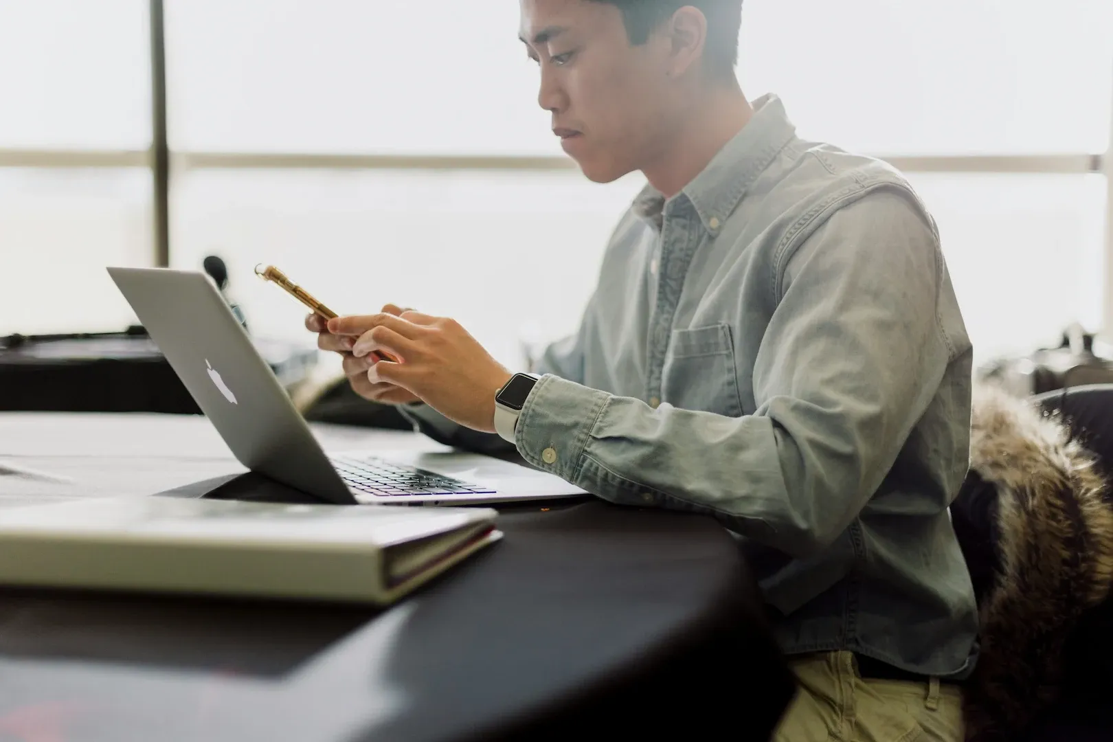 Student holding a pen while studying with a laptop and notebook